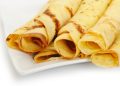 Crepe roll up a tubule on a plate. It is isolated on a white background.